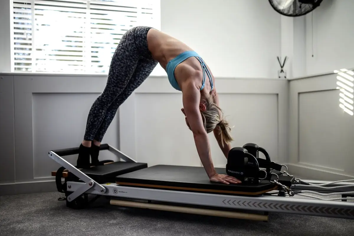 Woman performing an exercise on a reformer Pilates machine
